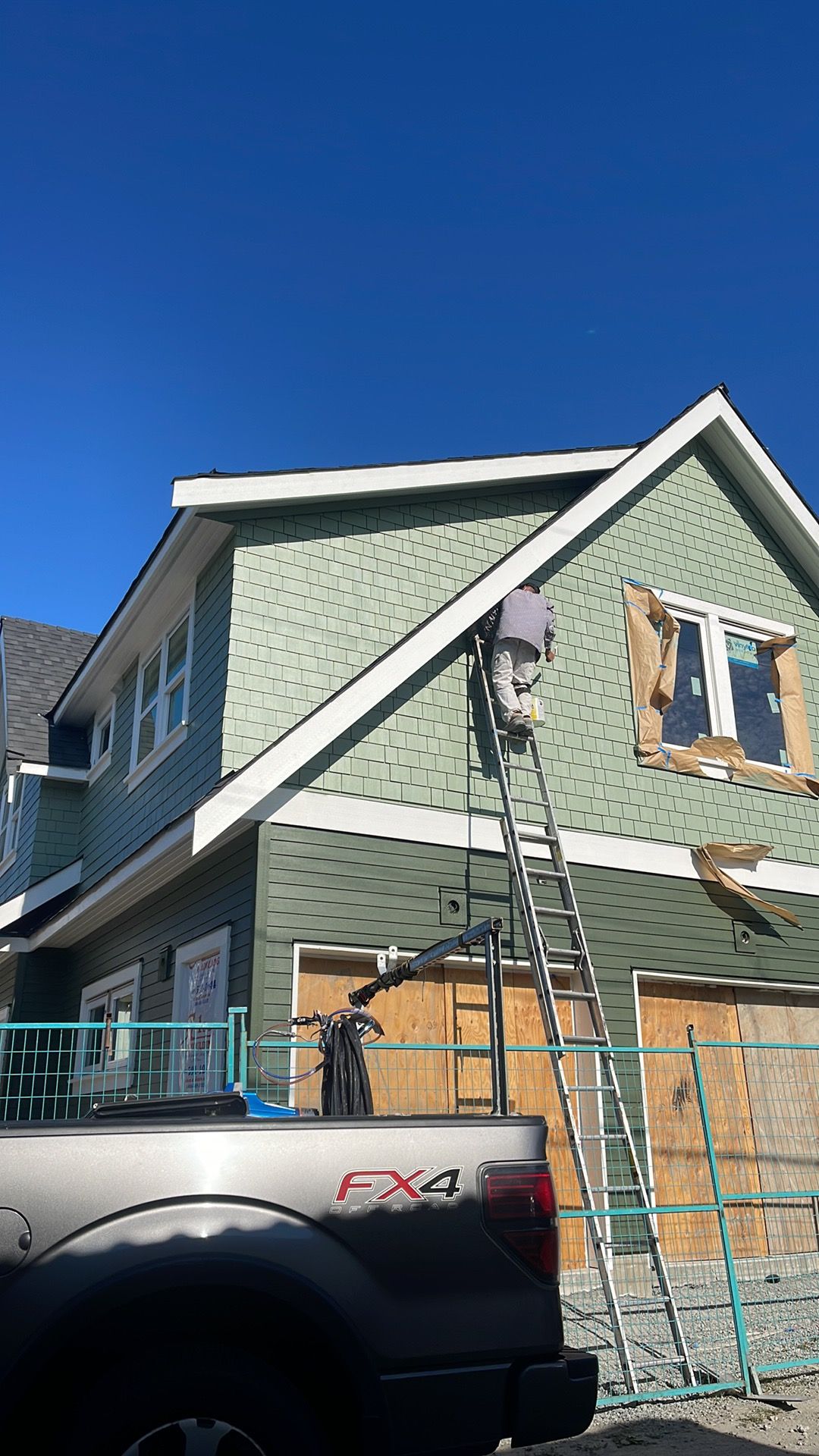 3 Pro Painting crew member painting a home exterior gable from a ladder